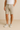 "Men’s name-brand beige chino shorts styled with white t-shirt and light gray sneakers, casual summer outfit modeled against a neutral background."