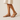 "Woman wearing beige flat leather sandals with ankle strap and gold buckle, styled with a cream midi dress, name-brand summer footwear modeled against a neutral background."