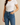"Woman wearing high-waisted blue skinny jeans and white fitted T-shirt, name-brand women’s denim modeled for casual everyday style against neutral background."