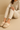 "Woman wearing plush beige memory foam slippers and cozy loungewear, name-brand women’s indoor footwear modeled for comfort and relaxation at home against neutral background."