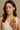 "Woman holding a luxury designer perfume bottle near her collarbone, wearing a sleeveless cream top, name-brand women’s fragrance modeled for elegant and minimalist beauty against a neutral background