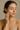 Woman applying white facial moisturizer to her cheek, showcasing name-brand women’s skincare routine with glowing complexion and minimal makeup against a neutral background