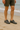 "Men’s gray mesh water shoes worn on sandy beach with ocean backdrop, name-brand quick-dry aquatic footwear modeled with green shorts for outdoor and travel use."